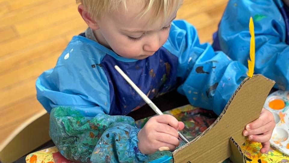 Children painting at easels in art class at Golden Minds Prep