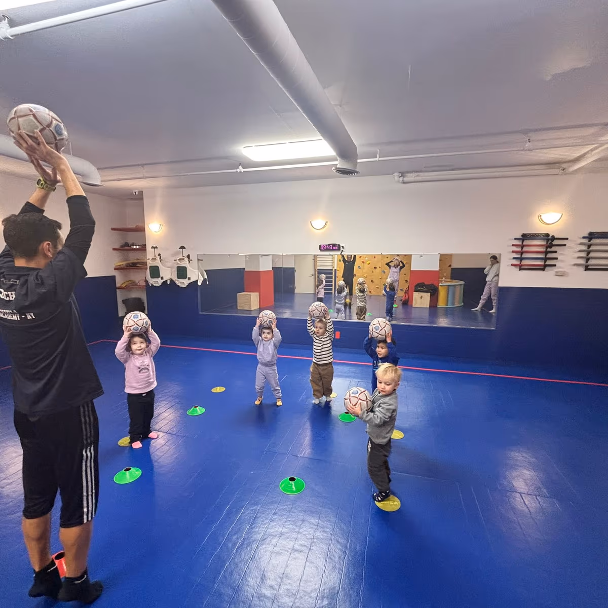 Child kicking a soccer ball into a goal at a preschool in FiDi.